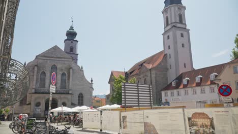 Día-Soleado-En-Lindau-Con-Vista-A-La-Iglesia-Histórica-Y-A-La-Animada-Cafetería-Al-Aire-Libre,-Cielo-Despejado