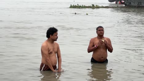 Toma-Estática-De-Hombres-Hablando-Del-Baño-Sagrado-Y-Rezando-En-Una-Brumosa-Mañana-De-Invierno-Durante-Sankranti-Con-Paisaje-Marino-Al-Fondo