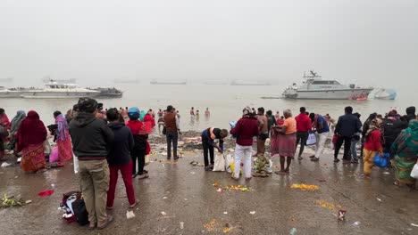 Toma-Estática-De-Gran-Angular-De-Personas-Bañándose-Y-Rezando-Durante-Sankranti-Cerca-De-Un-Embarcadero-En-Babughat,-Calcuta-Durante-La-Noche-Nublada