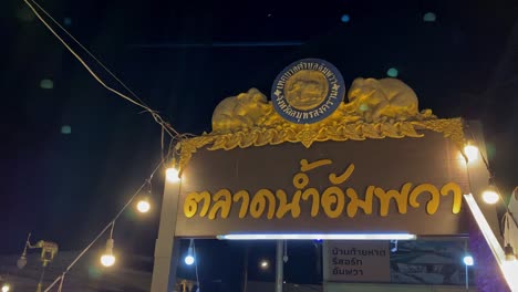 Nighttime-view-of-a-Thai-temple-gate-adorned-with-golden-sculptures,-illuminated-by-hanging-lights