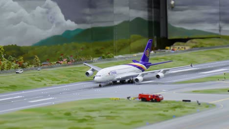 Vista-De-Perfil-De-Una-Exhibición-De-Un-Avión-De-Juguete-De-Thai-Airways-Despegando-En-El-País-De-Las-Maravillas-En-Miniatura-En-Hamburgo,-Alemania