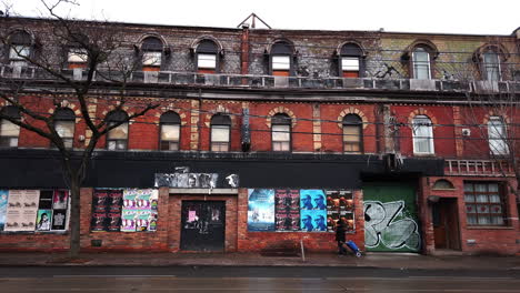 Lone-pedestrian-walks-in-front-of-an-abandoned-building-in-Parkdale,-Toronto