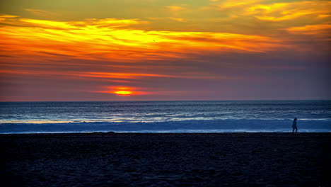 Goldener-Sonnenuntergang-Am-Meer-Im-Zeitraffer-Mit-Menschen,-Die-In-Silhouette-Am-Strand-Entlang-Spazieren