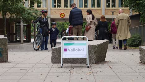 Pedestrians-near-voting-sign-in-Stockholm,-daytime,-election-atmosphere