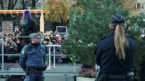 Manifestación-Pública-Con-Un-Orador-De-Pelo-Colorido-Y-Una-Policía-Atenta,-Ambiente-Otoñal,-Durante-El-Día,-Humor-Serio