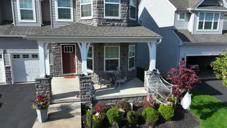 Modern-stone-house-in-USA-neighborhood-with-Halloween-decoration-on-porch-in-autumn