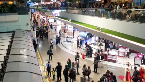 Vista-Interior-De-Personas-En-El-Edificio-De-La-Terminal-Del-Aeropuerto,-Comiendo-En-Cafés,-Comprando-En-Tiendas-Libres-De-Impuestos-Y-Personal-De-Vuelo-De-La-Aerolínea-Caminando-Con-Maletas-En-El-Aeropuerto-Internacional-Taoyuan-De-Taiwán