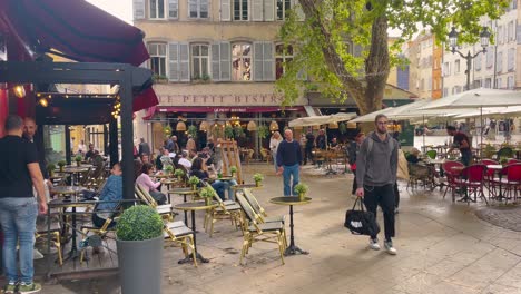 Animada-Cafetería-Al-Aire-Libre-En-Aix-en-Provence-Con-Clientes-Cenando,-Charlando,-Arquitectura-Europea-Como-Telón-De-Fondo,-Luz-Del-Día