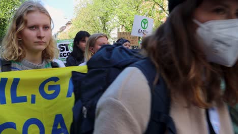 Crowd-of-activists-holding-signs-at-environmental-protest-in-Stockholm,-Sweden,-daylight,-urban-setting