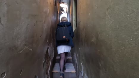 Young-woman-walking-on-the-Narrowest-Street-of-Prague,-Czech-Republic