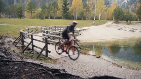 Un-Hombre-Andando-En-Bicicleta-Por-Las-Montañas-Y-Cruzando-Un-Puente-De-Madera