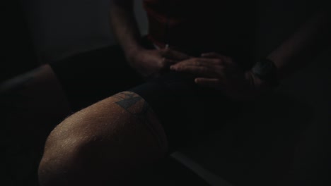 male-bicycle-rider-prepping-for-a-cycling-session,-dressing-up-in-dark-moody-morning-environment