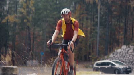 Ein-Männlicher-Radfahrer,-Der-In-Voller-Montur-Und-Helm-Mit-Seinem-Straßen-Schotterrad-In-Hohem-Tempo-Den-Berg-Hinauffährt