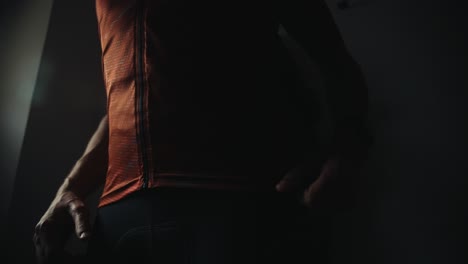 male-bicycle-rider-prepping-for-a-cycling-session,-dressing-up-in-dark-moody-morning-environment