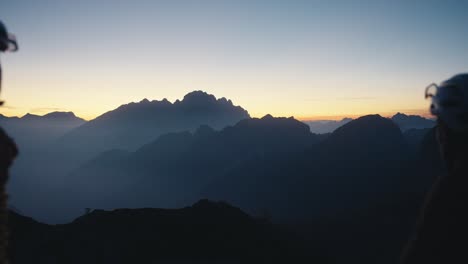 two-male-bicycle-riders-fist-bump-in-the-dark-sunset-in-the-mountains-on-the-top-of-the-hill