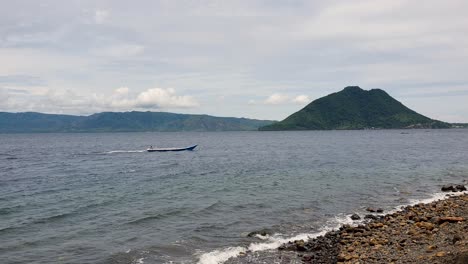 Vista-Panorámica-Del-Océano-En-La-Isla-De-Alor-En-El-Archipiélago-De-Alor,-Islas-Menores-De-La-Sonda-Oriental,-Con-Un-Pequeño-Barco-Pesquero-Y-Una-Isla-Tropical-Volcánica-En-El-Este-De-Nusa-Tenggara