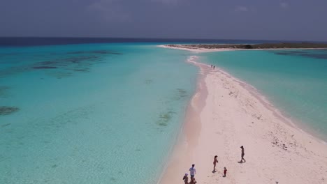 Sun-shade-and-people-gather-on-beautiful-sandy-stretch-connecting-tropical-islands-at-low-tide