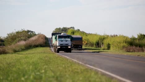 Konvois-Von-Lastwagen-Fahren-Auf-Einer-Landstraße-Mit-üppigem-Grün,-Sonniger-Tag