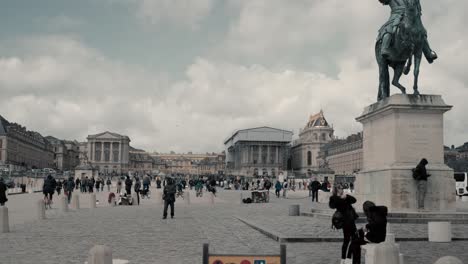 Estatua-Del-Rey-Luis-Xiv-A-Caballo-Frente-Al-Famoso-Castillo-Versalles-París-Francia-Con-Un-Hermoso-Cielo-Azul-Y-Nubes-Mientras-Muchos-Turistas-Y-Multitudes-Alrededor-Del-Castillo---Toma-Panorámica-Cinematográfica