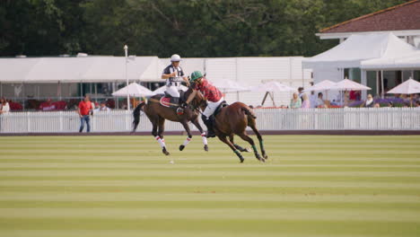 Polo-Schiedsrichter-Reitet-An-Einem-Spieler-Vorbei,-Der-Den-Ball-Mit-Einem-Rückschwung-Schlägt