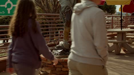 Native-American-woman-with-baby-in-papoose-sculpture-in-downtown-Sedona,-Arizona-with-people-walking-by-and-video-tilting-down