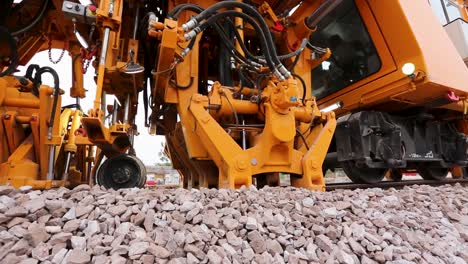 Close-up-of-a-yellow-excavator's-hydraulic-arm-moving-crushed-stone,-daylight