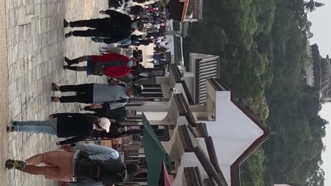 Vertical-footage-of-tourists-visiting-the-Big-Buddha-Ngong-Ping-Village,-Lantau-Island