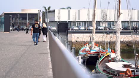 Gente-Caminando-Por-El-Paseo-Marítimo-De-Recreo,-Ferrocarril-Borroso-En-Primer-Plano