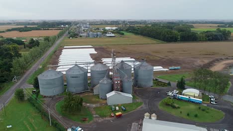 Getreidesilos-Auf-Einem-Bauernhof-Mit-Umgebendem-Grün,-Bewölkter-Tag,-Landwirtschaftliche-Lagerung,-Luftaufnahme