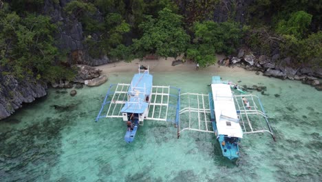 Island-hopping-tour-boats-at-skeleton-wreck-and-people-having-lunch-on-Malwawey-island,-Drone-reveal