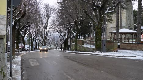 Trees-under-snow-on-the-streets-of-Guardiagrele-as-cars-drive-by,-Abruzzo,-Italy