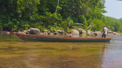 Dos-Lugareños-Navegando-En-Canoa-Por-Las-Cristalinas-Aguas-De-Oxapampa,-Perú,-Rodeados-De-Exuberante-Vegetación.