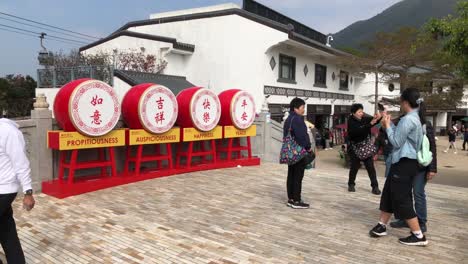 Los-Turistas-Toman-Fotografías-Junto-A-Una-Exhibición-En-La-Aldea-De-Ngong-Ping,-Hong-Kong.