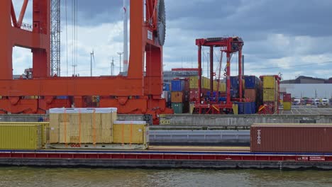 Parallax-aerial-view-of-cranes-helping-at-moving-cargoes-at-commercial-port-of-Hamburg,-Germany-during-a-cloudy-day