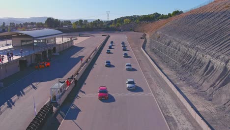 Coches-Alineados-En-El-Circuito-De-Velocidad-Castelloli,-Barcelona,-España,-Con-Espectadores,-Vista-Aérea.