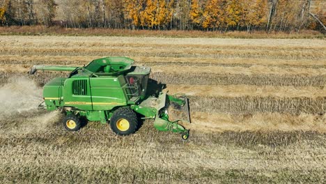 Tracking-Drohnenaufnahme-Eines-John-Deere-Mähdreschers,-Der-Einen-Rapsschwad-Aufnimmt