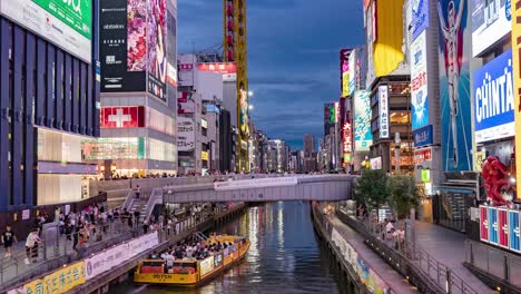 Lapso-De-Tiempo-Nocturno-De-Barcos-Que-Pasan,-Personas-Y-Letreros-Iluminados-En-El-Puente-Ebisu-Canal-Dotonbori-Namba-Osaka,-Japón