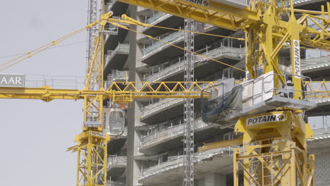 Una-Observación-De-Un-Rascacielos-En-Construcción,-Ascendiendo-A-Un-Mínimo-De-100-Metros,-Acompañado-De-Grúas-Amarillas-Trabajando-Diligentemente-En-Este-Impresionante-Edificio