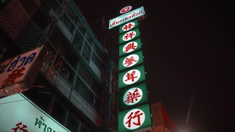 Un-Brillante-Cartel-De-Neón-Chino-Cuelga-De-Un-Antiguo-Edificio-En-Chinatown,-Bangkok