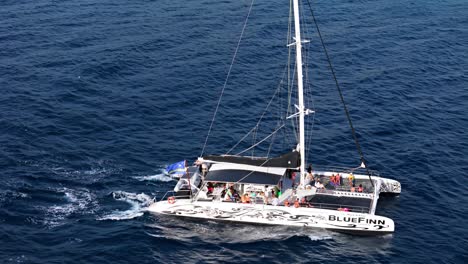 Curacao-flag-waves-in-wind-off-back-of-catamaran-in-deep-blue-ocean