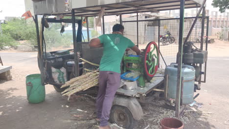 Un-Vendedor-De-Caña-De-Azúcar-Convierte-Su-Auto-rickshaw-En-Un-Puesto-Ambulante-De-Jugo,-Extrayendo-Jugo-Fresco-De-Caña-De-Azúcar-Para-Los-Transeúntes-Sedientos,-Mostrando-Espíritu-Emprendedor-Y-Comercio-Callejero-Innovador.