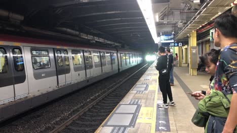 Couple-wait-to-board-the-train-at-the-MTR-station-at-Tai-Po-in-New-Provinces,-Hong-Kong