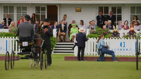 Queen-Elizabeth-II-in-a-green-dress-watches-as-carriages-are-judged-in-an-annual-show