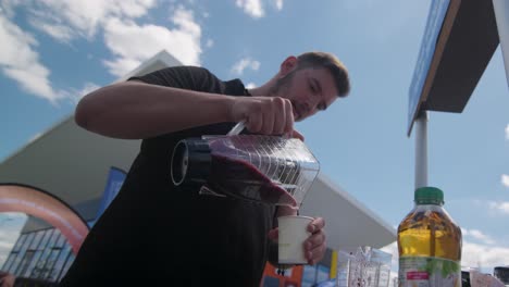 Low-Angle-Ansicht-Eines-Jungen-Mannes,-Der-Bei-Klarem-Himmel-Bei-Der-Tour-De-France-In-Frankreich-Smoothie-In-Ein-Glas-Gießt