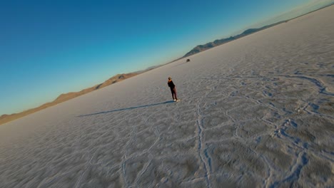 Drone-FPV-Volando-Alrededor-Del-Operador-Y-La-Conducción-De-Automóviles-En-Las-Salinas-De-Bonneville-En-Utah-Durante-La-Hora-Dorada