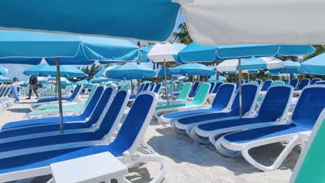 Relax-in-Caribbean-style:-Empty-beach-chairs-and-umbrellas-adorn-the-sandy-shores-against-the-backdrop-of-azure-waters-and-skies,-epitomizing-tropical-tranquility