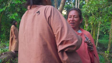 Two-indigenous-women-embracing-in-a-lush-forest,-Oxapampa,-Peru,-conveying-a-sense-of-community-and-warmth