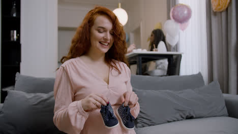 Pregnant-woman-holding-baby-shoes