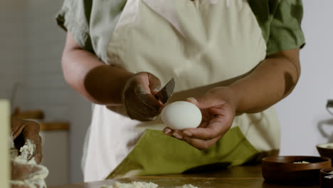 Woman-cracking-egg-on-the-dough