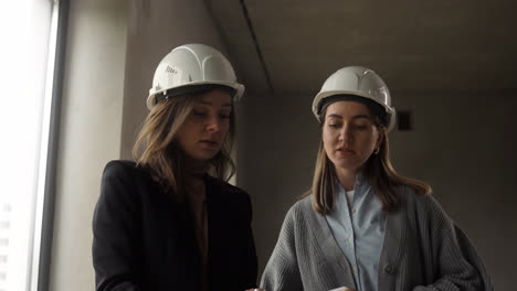 Frauen-Mit-Bauhelmen-In-Einem-Leeren-Haus